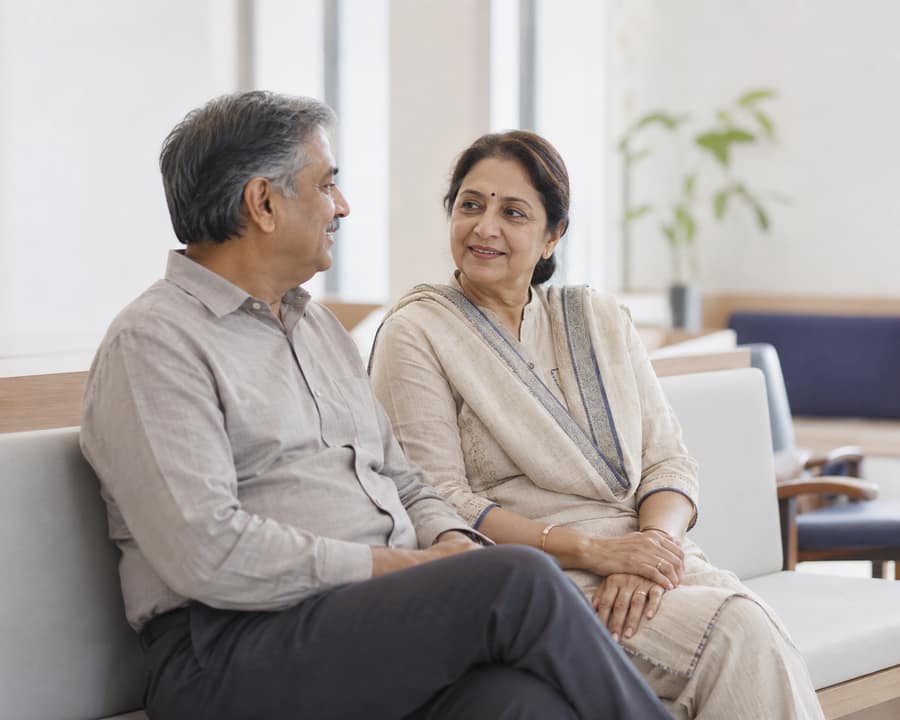 A couple in their fifties waiting together in a bright waiting area